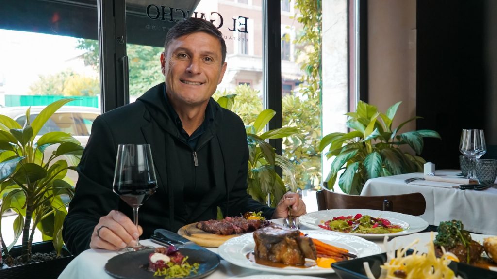Javier Zanetti seduto al tavolo di KU by El Gaucho con un calice in mano durante l’inaugurazione a Laveno.